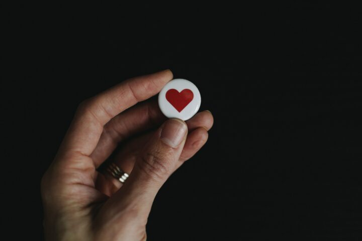 Hand holding a heart pin