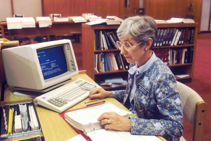 lady writing looking IT monitor system glasses